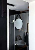 Petit lavabo monochrome reflété dans le verre de la cabine de douche