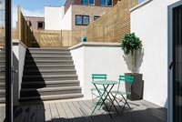 Table et chaises de café vert sur une terrasse moderne avec jardin sur deux niveaux