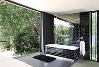 Salle de bain attenante monochrome moderne avec portes coulissantes ouvertes sur le jardin