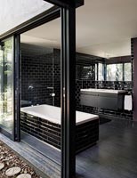 Salle de bain attenante monochrome moderne avec portes coulissantes ouvertes sur le jardin