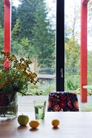 Fleurs, fruits et verre sur table devant fenêtre