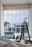 Télescope à côté d'une fenêtre avec vue sur la mer