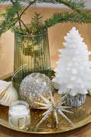 Détail de décorations de Noël en verre or et blanc sur plateau.