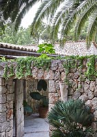 Mur de pierres sèches et grande passerelle en bois cloutée vers le jardin