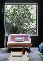 Chaise vintage rose dans une chambre moderne avec grande baie vitrée
