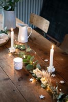 Guirlandes et bougies sur table à manger en bois au moment de Noël