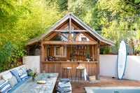 Bar en bois et grande table en bois dans le jardin de la cour avec piscine