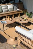 Terrasse ensoleillée avec mobilier en bois, tapis et coussins