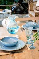 Détail de la vaisselle bleue et de la verrerie sur la table à manger en plein air