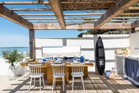 Planche de surf dans une cuisine-salle à manger extérieure donnant sur la mer