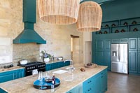 Cuisine de campagne moderne avec boiseries peintes bleu sarcelle et murs en pierres apparentes