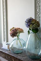 Fleurs coupées dans de grands vases en verre sur une cheminée en marbre