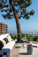 Coin salon sur une terrasse en bois avec vue sur la mer au-delà