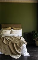 Literie crème dans une chambre peinte en vert foncé