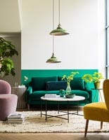 Salon moderne avec mur à moitié peint en vert derrière le canapé