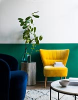 Salon moderne avec mur à moitié peint en vert derrière une chaise jaune