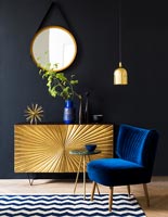 Buffet doré et chaise bleue dans le salon peint en noir
