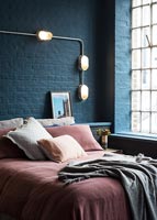 Literie rose et brique peinte bleu foncé dans une chambre moderne