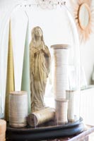 Bobines de coton, bougies et statuette en or sous coupole en verre