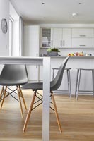 Chaises grises en cuisine-salle à manger moderne blanc avec plancher en bois