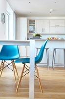 Chaises turquoise en cuisine-salle à manger moderne blanc avec plancher en bois