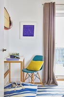 Coussin jaune sur une chaise bleu sarcelle dans une chambre côtière moderne