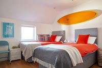 Planche de surf orange vif au-dessus des lits jumeaux