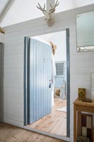 Vue à travers une porte en bois ouverte vers une salle de bains attenante depuis une chambre de campagne moderne