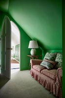 Canapé en vichy rouge dans une chambre peinte en vert