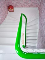 Vue vers le bas de l'escalier blanc avec rampe peinte en vert et papier peint rose