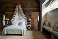 Chambre de campagne avec mur en bois et auvent sur lit