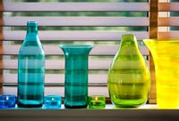 Collection de verrerie colorée sur le rebord de la fenêtre avec des bougies chauffe-plat