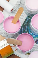 Pots de peinture avec différentes nuances de rose poussiéreux, pinceaux et rouleaux