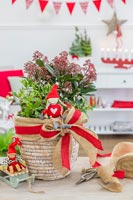 Décoration de table de Noël plantée de Skimmia et Holy ornée de ruban rouge et d'arc de Hesse et de figurines nordiques