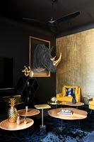 Salon éclectique avec murs peints en noir et tête de trophée Rhino en tissu sur le mur