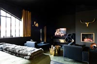 Chambre moderne avec murs peints en noir, télévision et cheminée
