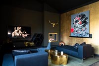 Chambre moderne noire et or avec des œuvres d'art colorées et un grand coin salon