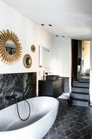Baignoire sur pied dans la salle de bains monochrome moderne avec des marches jusqu'à la chambre