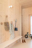 Couloir moderne revêtu de bois avec grands patères et banc