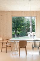 Salle à manger de campagne en bois moderne avec grande baie vitrée et vue sur le jardin