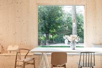 Salle à manger en bois moderne avec grande baie vitrée donnant sur jardin