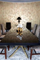 Salle à manger moderne avec un mur en or reflété sur une table laquée noire