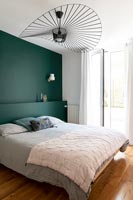 Mur et tête de lit peints sarcelle dans une chambre moderne