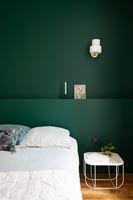 Mur et tête de lit peints en vert foncé dans la chambre moderne