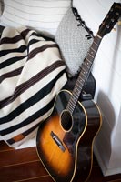 Gros plan de la guitare à côté de couvertures et coussins