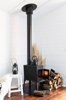 Poêle à bois noir dans un salon de style cottage en bois peint en blanc