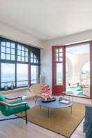 Salon moderne avec portes-fenêtres ouvertes sur terrasse et vue sur la mer