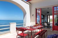 Table à manger rouge sur terrasse blanche avec vue sur la mer