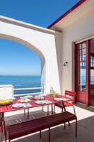 Terrasse rouge et blanche avec vue sur la mer - table à manger dressée pour le déjeuner