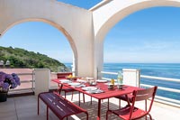 Table à manger rouge dressée pour le déjeuner sur la terrasse avec vue sur la mer en été
